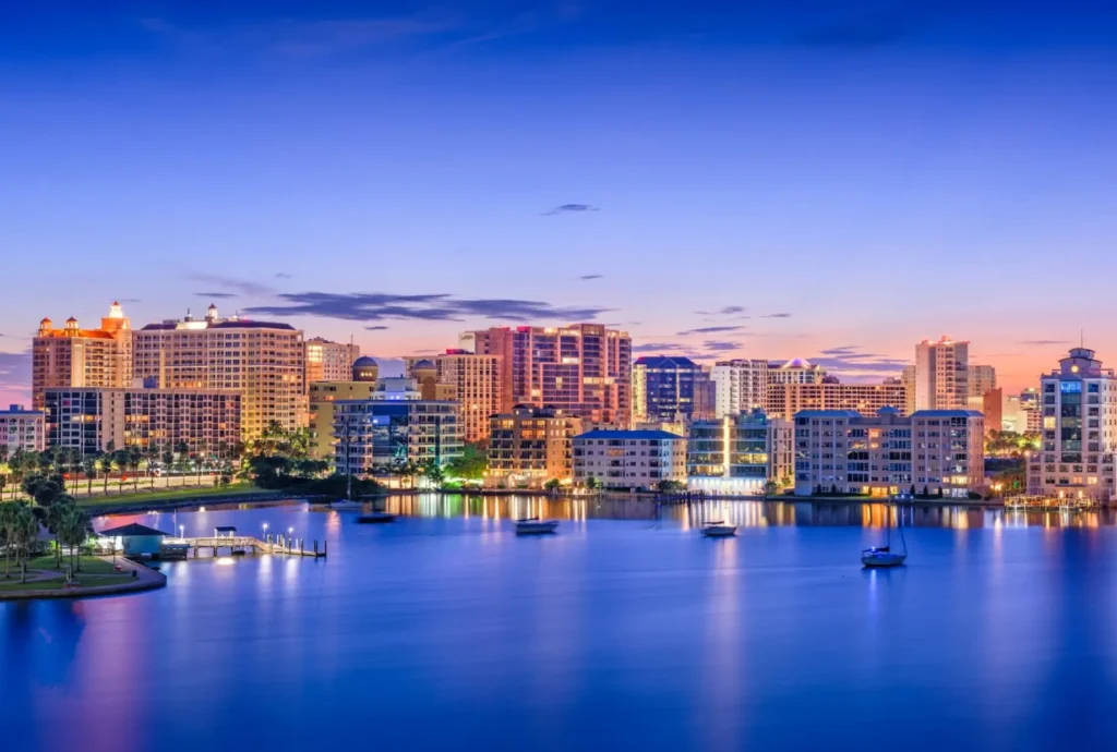 A view of the Sarasota coastline at dusk with buildings lit up.